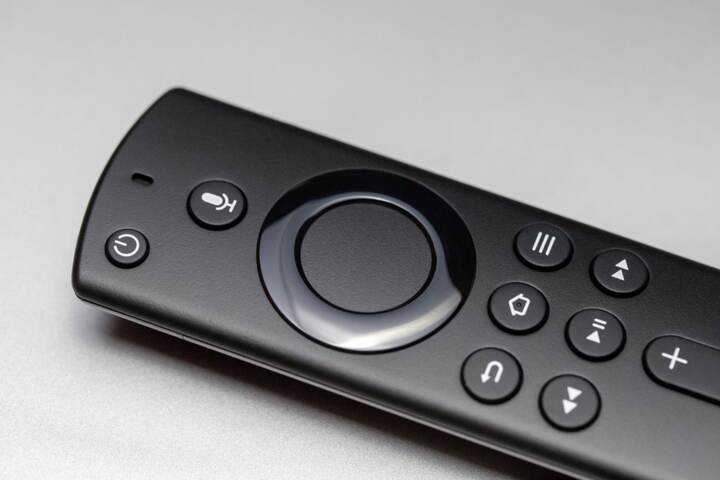 白い机の上に斜めに置かれた黒いテレビ用リモコン